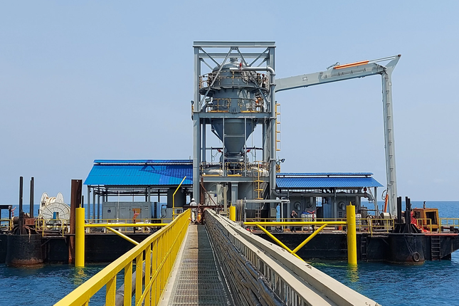 Offshore dry bulk transfer terminal on a barge, with cyclone separator, hopper and loading boom